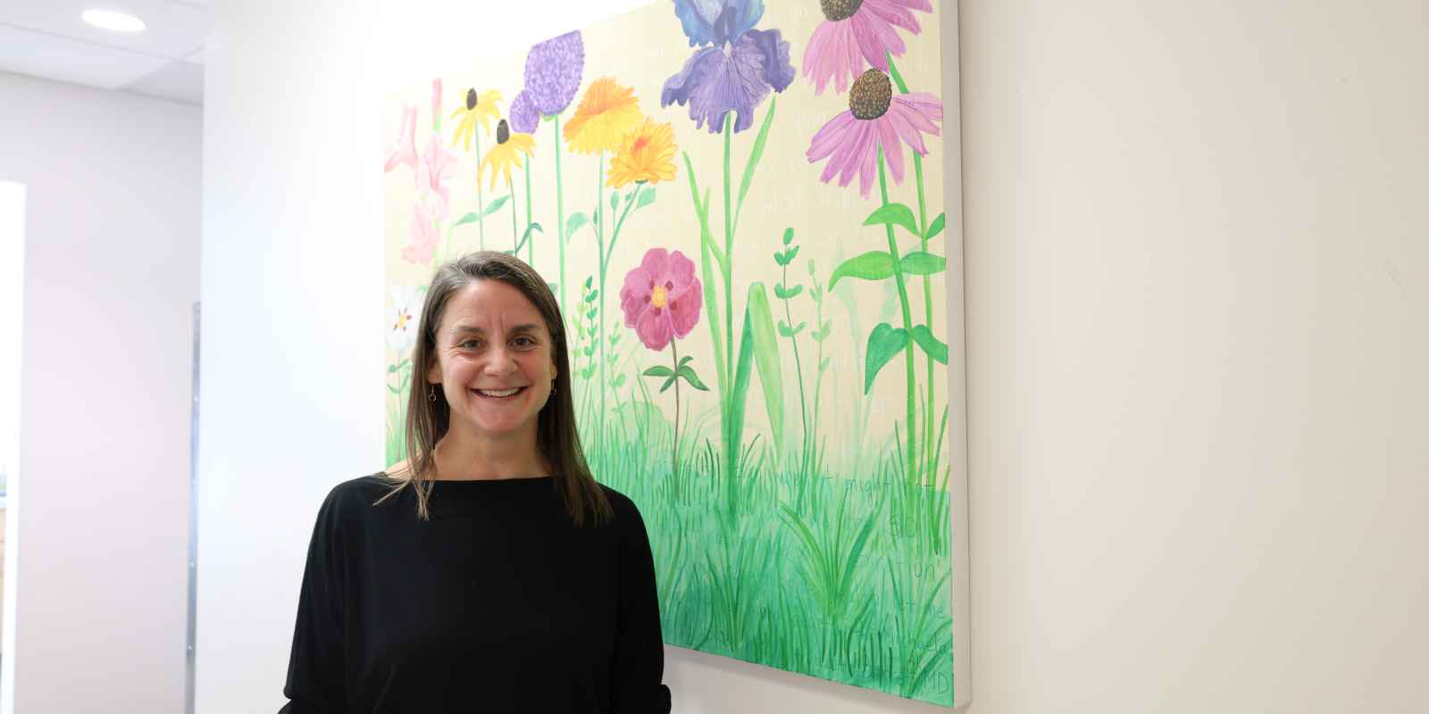 Andrea Downs stands in front of her painting Waystation