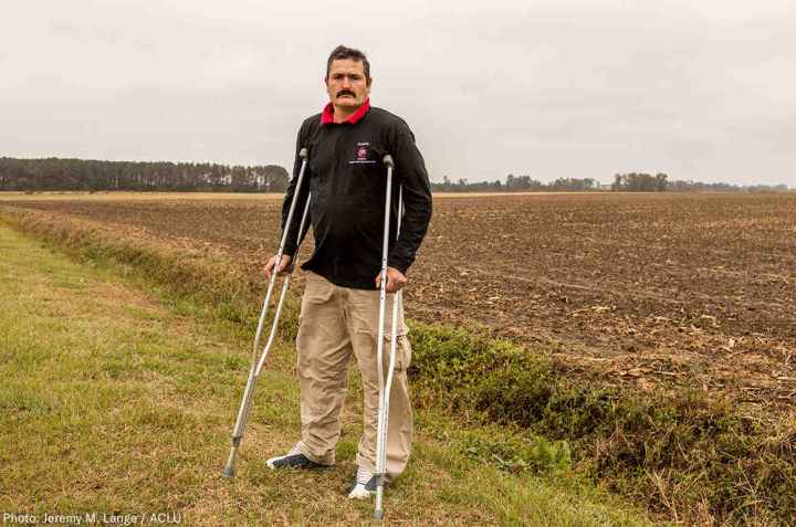 Arturo Hernandez stands on crutches in a field in North Carolina.