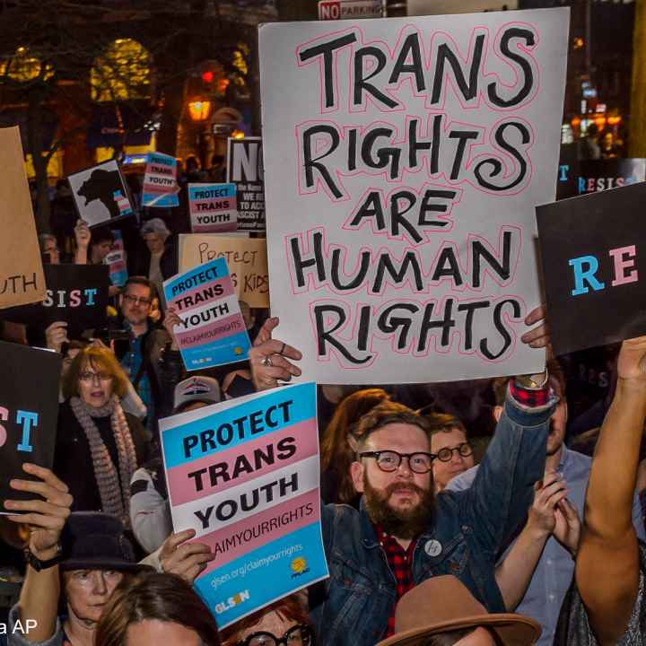 Protestors with signs advocating for the rights of trans youth.