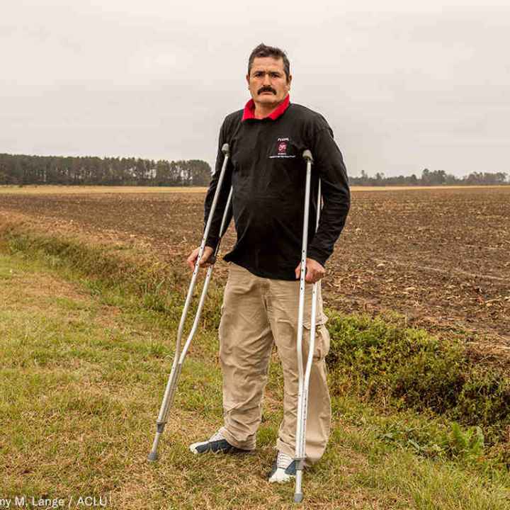 Arturo Hernandez stands on crutches in a field in North Carolina.